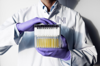 Nightingale Health laboratory specialist holding a sample rack with both hands.
